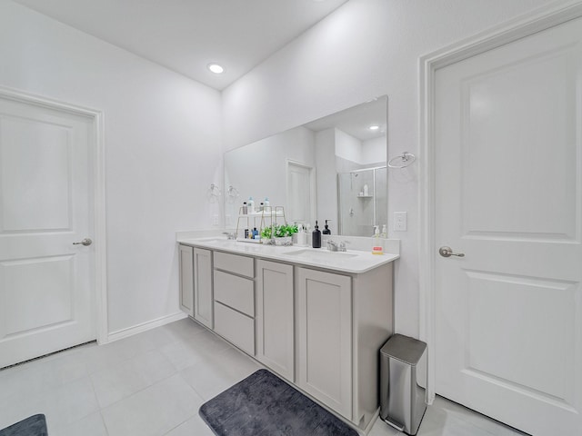 bathroom featuring double vanity, baseboards, tile patterned flooring, a shower stall, and a sink