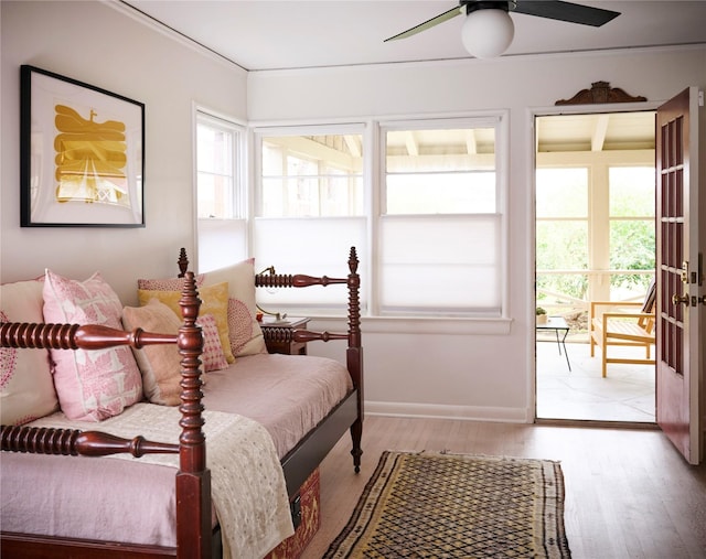 bedroom featuring light wood-type flooring, multiple windows, baseboards, and a ceiling fan