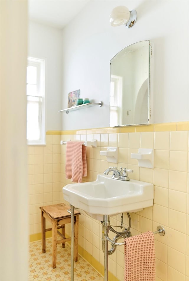 half bath with a sink, tile walls, and wainscoting