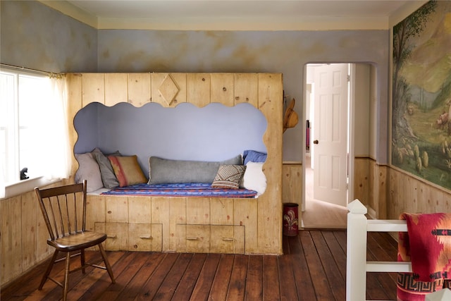 bedroom featuring a wainscoted wall, ornamental molding, hardwood / wood-style flooring, and wood walls