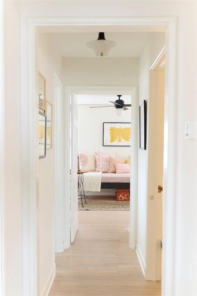 hallway featuring light wood-style floors and baseboards