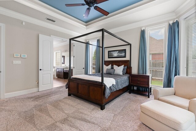 bedroom featuring crown molding, carpet flooring, a raised ceiling, ensuite bath, and baseboards