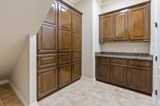 kitchen featuring light tile patterned flooring, ornamental molding, and baseboards
