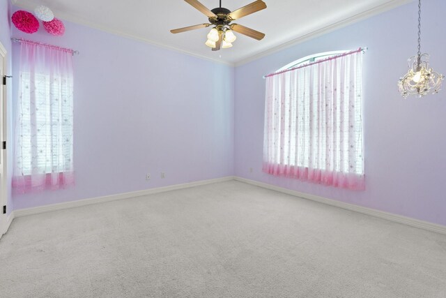 carpeted spare room featuring ornamental molding, a chandelier, a ceiling fan, and baseboards