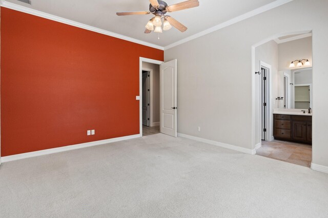 unfurnished bedroom featuring light carpet, crown molding, baseboards, a sink, and ensuite bath