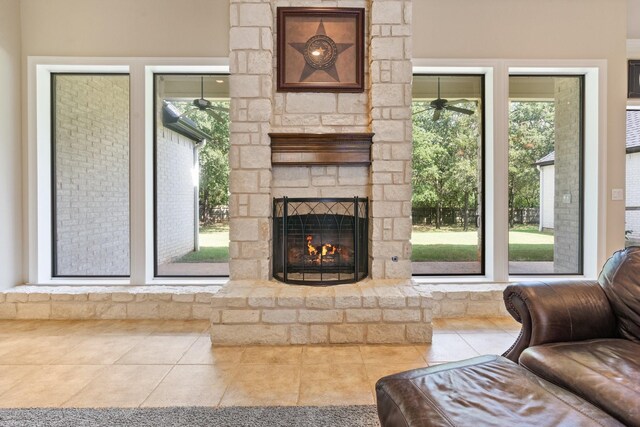 living room with ceiling fan, tile patterned flooring, and an outdoor stone fireplace