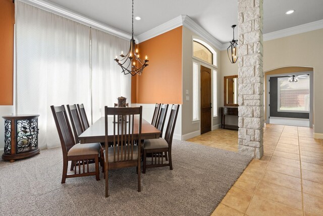 tiled dining space with ornate columns, crown molding, a chandelier, arched walkways, and baseboards