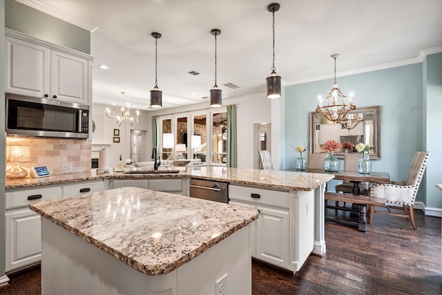 kitchen featuring appliances with stainless steel finishes, a kitchen island, a sink, a chandelier, and a peninsula