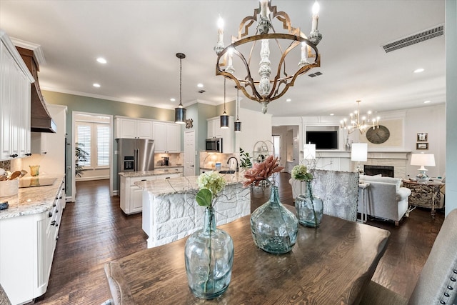 dining room with a chandelier, dark wood-type flooring, a fireplace, and visible vents