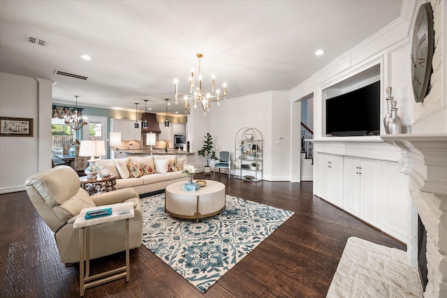 living room featuring dark wood-style floors, recessed lighting, visible vents, an inviting chandelier, and a fireplace with flush hearth