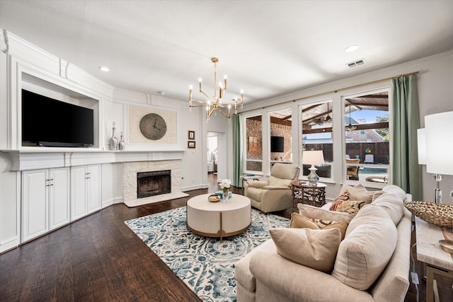 living area featuring a chandelier, a stone fireplace, wood finished floors, visible vents, and crown molding