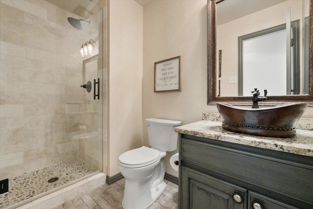 full bathroom featuring a stall shower, baseboards, vanity, and toilet