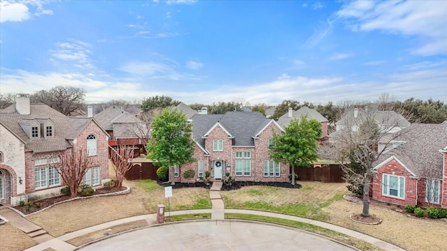 view of front of property with a residential view, brick siding, fence, and a front lawn