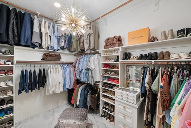 walk in closet featuring marble finish floor and a chandelier