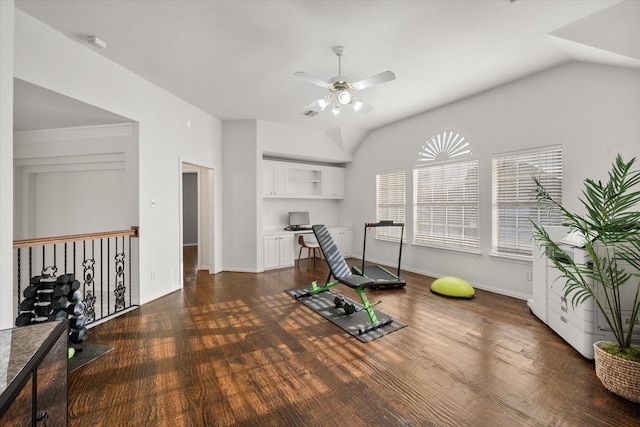 exercise room with dark wood-style flooring, vaulted ceiling, built in desk, and baseboards