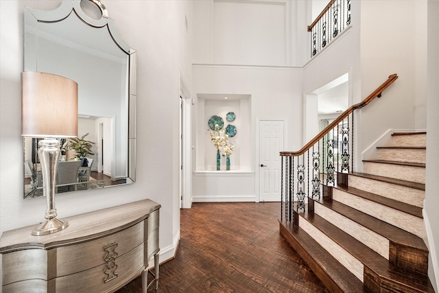 foyer with a towering ceiling, baseboards, stairway, and dark wood-style flooring