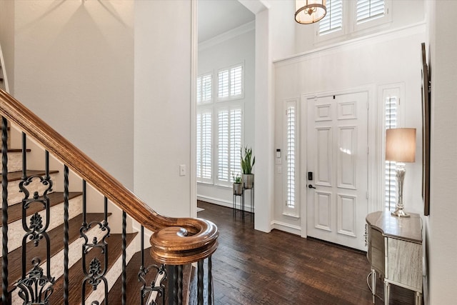 entryway featuring a high ceiling, ornamental molding, dark wood-type flooring, baseboards, and stairs