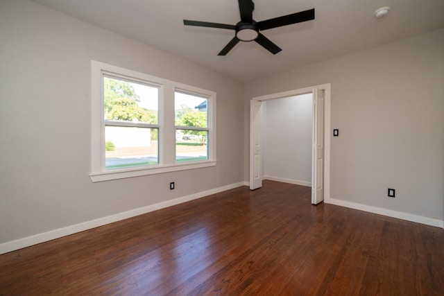 empty room featuring ceiling fan, dark wood-type flooring, and baseboards