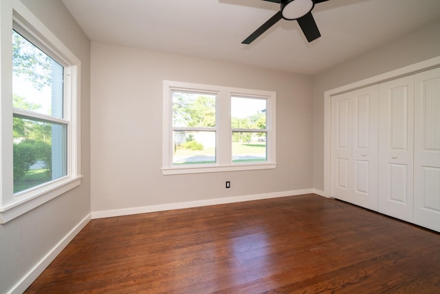 unfurnished bedroom featuring dark wood-style floors, ceiling fan, a closet, and baseboards