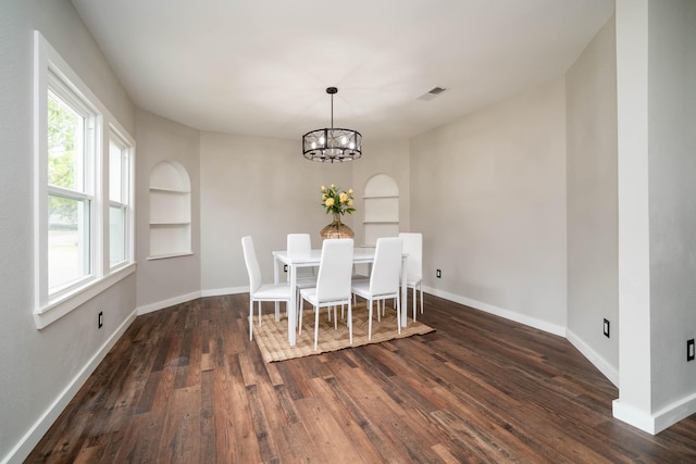 unfurnished dining area with a chandelier, built in shelves, dark wood-style flooring, visible vents, and baseboards