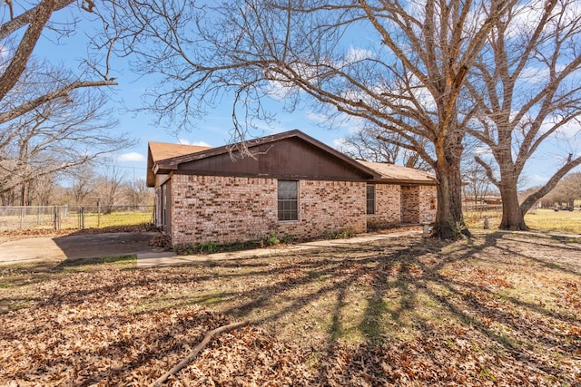 view of side of property featuring brick siding and fence