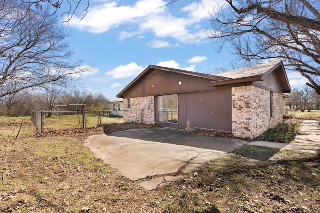 view of property exterior featuring a patio area, fence, and brick siding