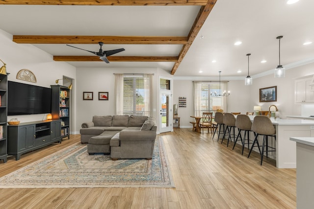 living area featuring light wood-type flooring, baseboards, beamed ceiling, and ceiling fan with notable chandelier