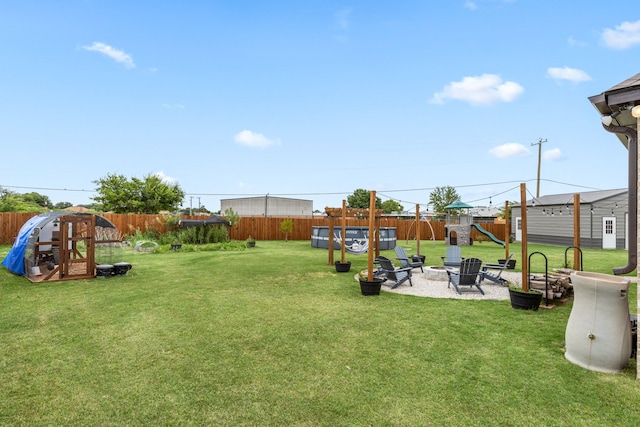 view of yard with a patio area, a fenced backyard, a fire pit, and a playground