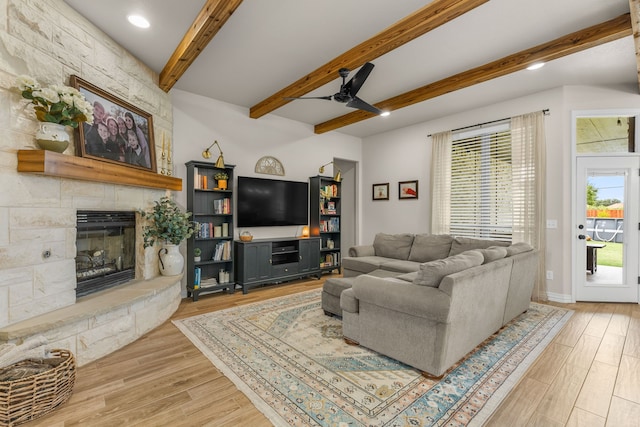 living room featuring a fireplace, wood finished floors, beam ceiling, and a ceiling fan