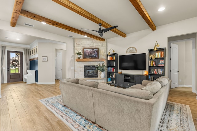 living area featuring visible vents, ceiling fan, a stone fireplace, and light wood finished floors