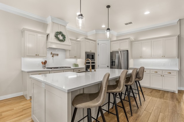 kitchen with light countertops, visible vents, light wood-style flooring, appliances with stainless steel finishes, and a sink