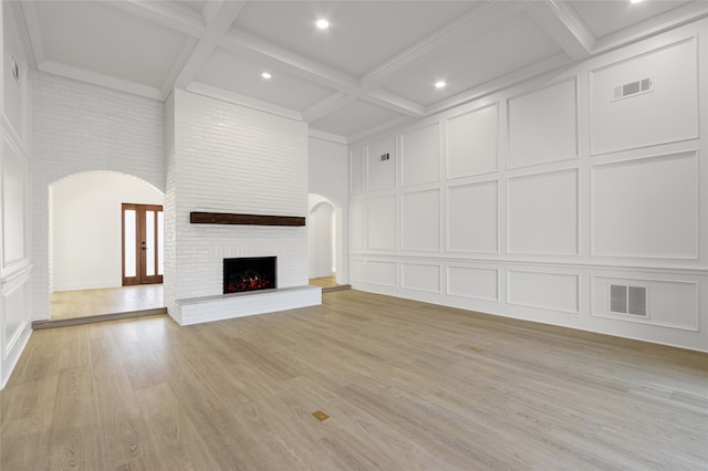 unfurnished living room with arched walkways, visible vents, a decorative wall, and a fireplace