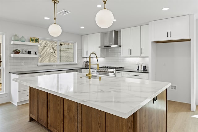 kitchen featuring tasteful backsplash, visible vents, light wood-style flooring, wall chimney range hood, and open shelves