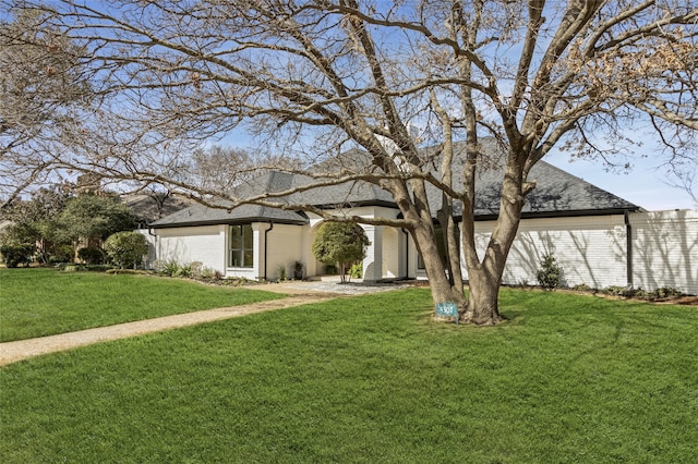 mid-century home with brick siding, a front lawn, and roof with shingles