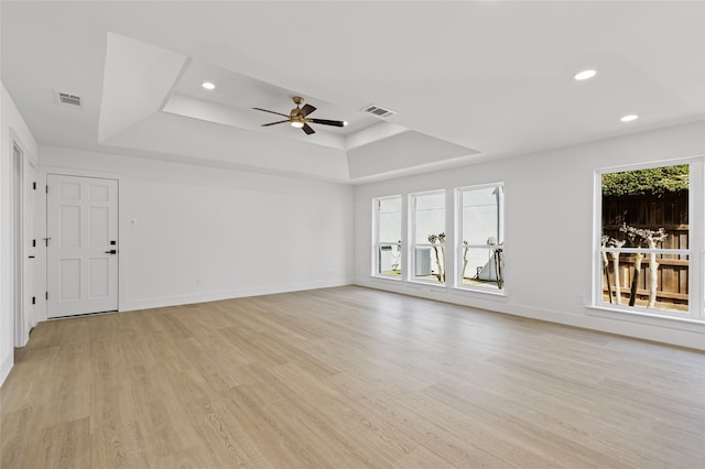 unfurnished living room featuring recessed lighting, a raised ceiling, light wood-style flooring, and baseboards