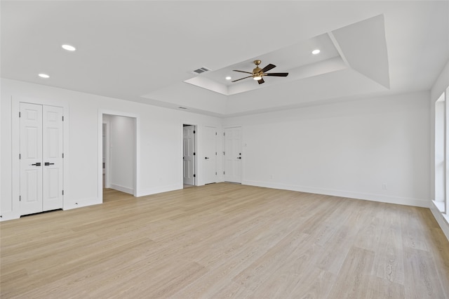 empty room featuring light wood finished floors, baseboards, and a raised ceiling