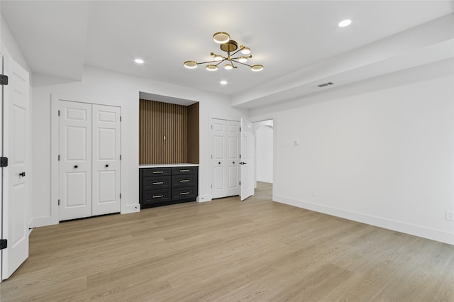 unfurnished bedroom with recessed lighting, baseboards, light wood finished floors, and two closets