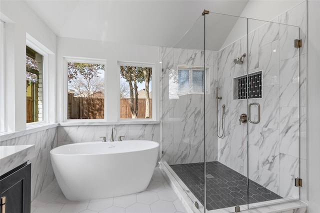 bathroom with vaulted ceiling, vanity, a freestanding tub, and a marble finish shower