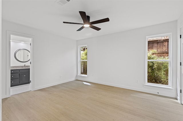 unfurnished bedroom featuring ceiling fan, ensuite bathroom, visible vents, baseboards, and light wood-style floors