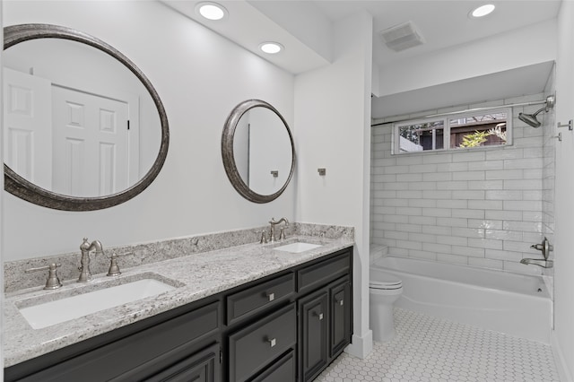 bathroom featuring visible vents, double vanity, a sink, and toilet