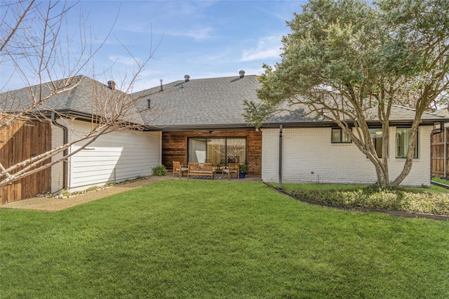 rear view of house with brick siding, fence, a yard, roof with shingles, and a patio area