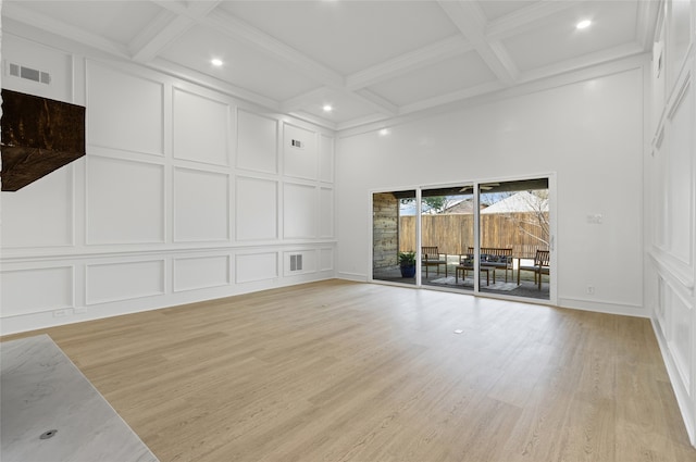 unfurnished living room with coffered ceiling, beam ceiling, and a decorative wall