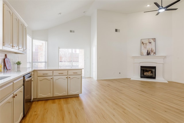 kitchen with visible vents, stainless steel dishwasher, a glass covered fireplace, open floor plan, and a peninsula