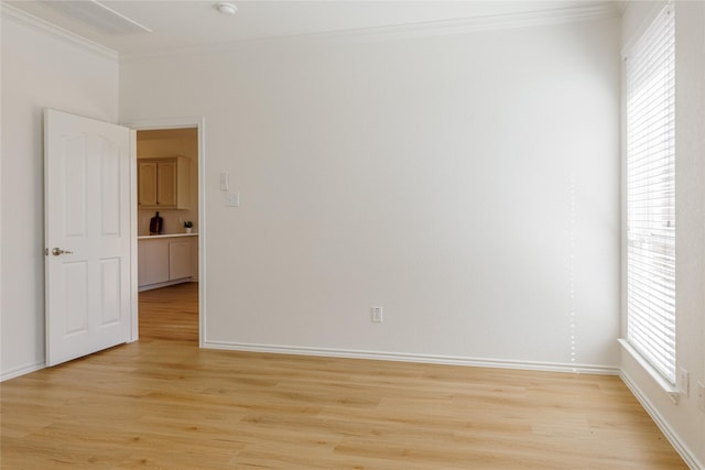 unfurnished room featuring light wood finished floors, baseboards, and crown molding