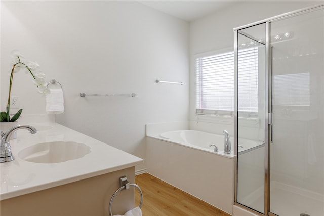 full bath featuring double vanity, a stall shower, wood finished floors, a sink, and a bath