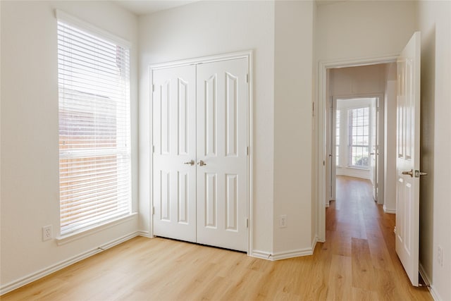 unfurnished bedroom featuring light wood-style floors, a closet, and baseboards