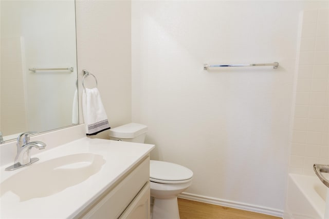 bathroom featuring toilet, baseboards, wood finished floors, and vanity