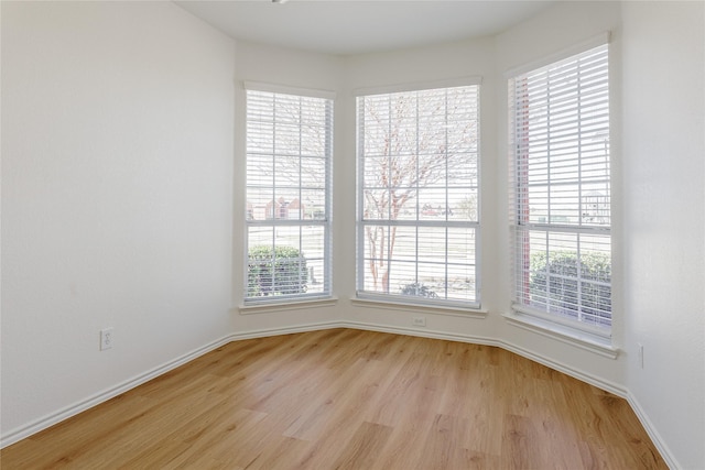 unfurnished room with light wood finished floors and baseboards