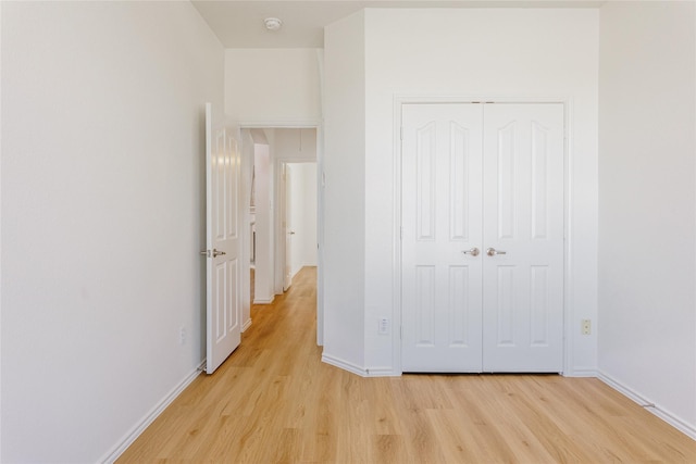 unfurnished bedroom featuring a closet, baseboards, and light wood finished floors