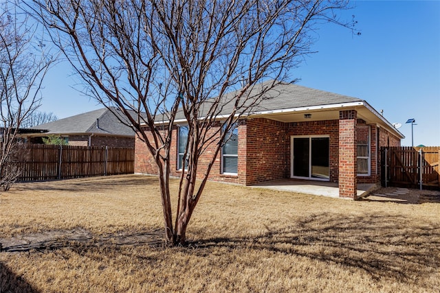 rear view of property featuring a patio area, a fenced backyard, a lawn, and brick siding